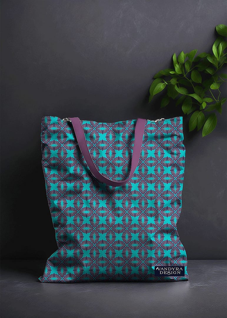 Stoffdesign. Tasche mit geometrischem Fledermausmuster in Hellblau und Lila. Hintergrund ist ein dunkles Grau und als Deko sieht man eine Pflanze. Auf dem Bild ist das Label - der Schriftzug Vandyra Design von der Designerin zusehen.