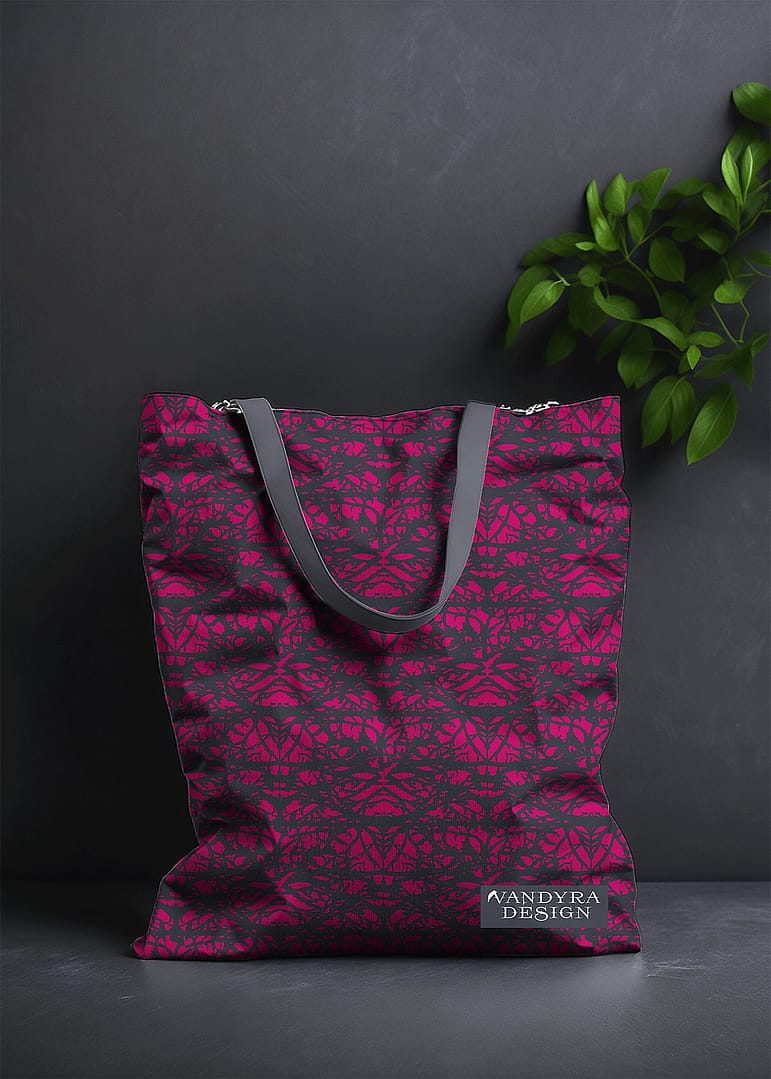 Stoffdesign. Tasche mit mystischem Muster. Motiv eines verschlungenen Greenman und Motten. Das Muster ist schwarz-pink. Auf dem Bild ist das Label - der Schriftzug Vandyra Design von der Designerin zusehen. Der Hintergrund ist dunkelgrau und als Deko sieht man eine Pflanze zum Teil abgebildet.