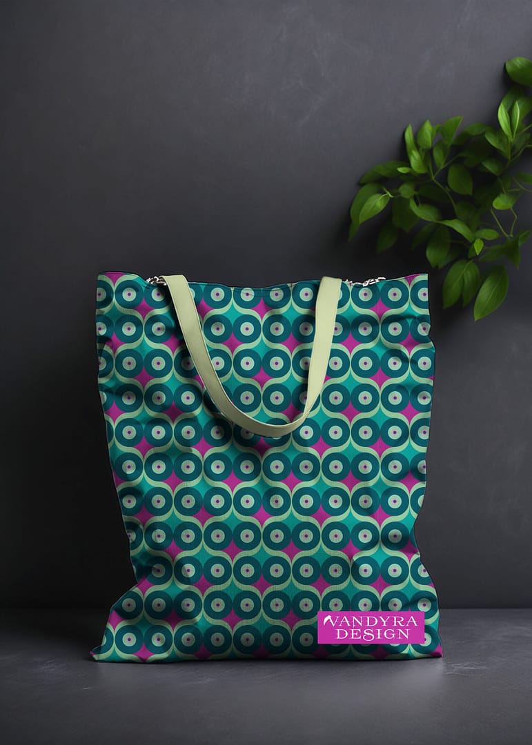 Stoffdesign. Tasche mit geometrischem Eulenmuster. Die Farben auf dem Muster sind Mint-Hellgrün-Dark Cyan und Fuchsia. Auf dem Bild ist das Label - der Schriftzug Vandyra Design von der Designerin zusehen. Der Hintergrund ist dunkelgrau und als Deko sieht man eine Pflanze zum Teil abgebildet.