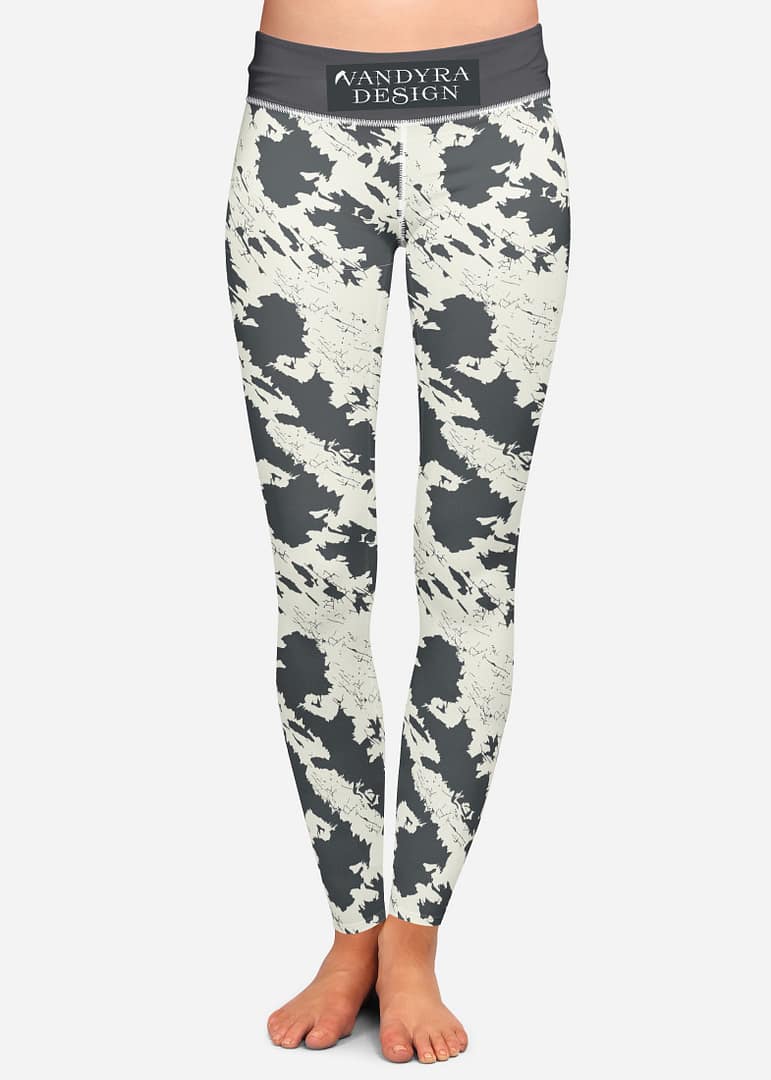 Leggings von vorn mit abstraktem Black-Off-White Muster, die Füße sind zu sehen. Auf dem Bild ist das Label - der Schriftzug Vandyra Design von der Designerin zusehen. Der Bildhintergrund ist ein sehr helles Grau.